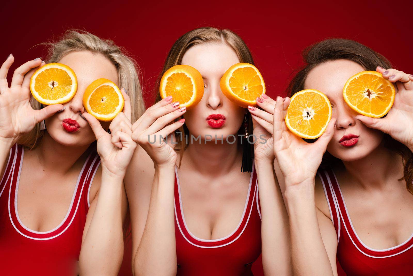 Beautiful female model posing on red background by StudioLucky