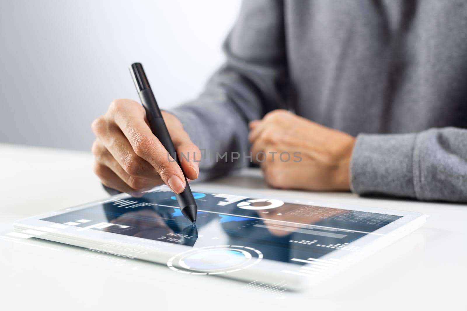 Woman using tablet computer for project management. Close-up of female hand holding pen and touching screen of tablet device. Online stock trading and investing. Mobile smart device in business