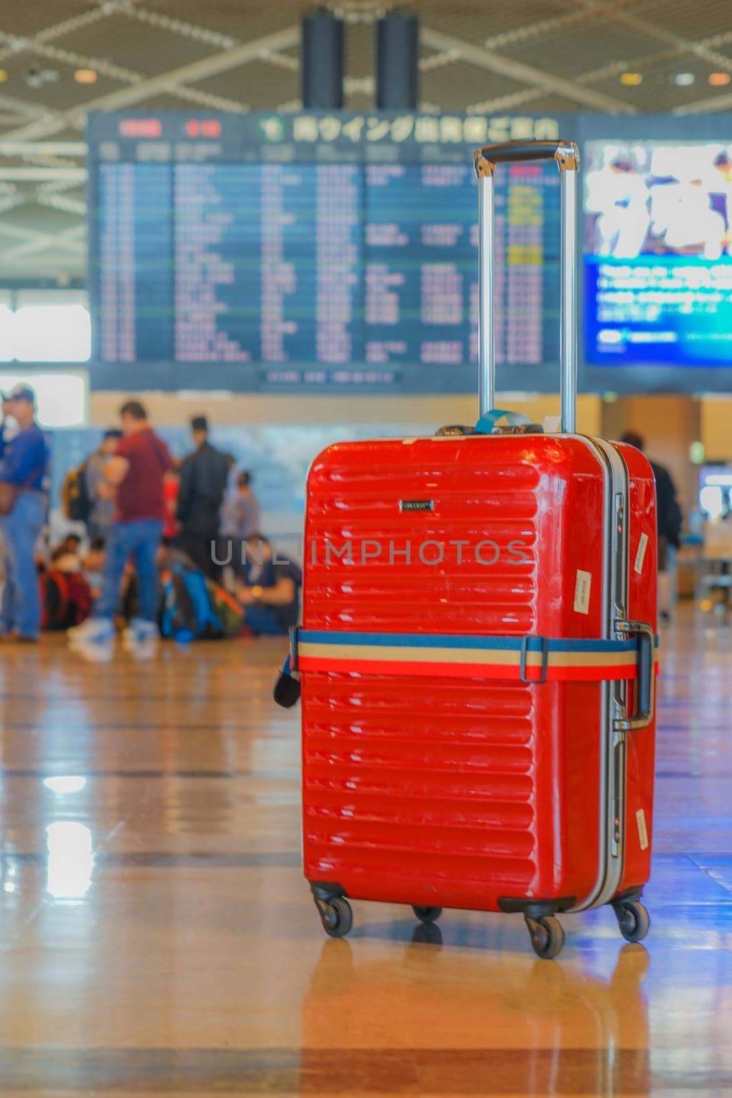 Red suitcase placed at the airport. Shooting Location: Tokyo metropolitan area