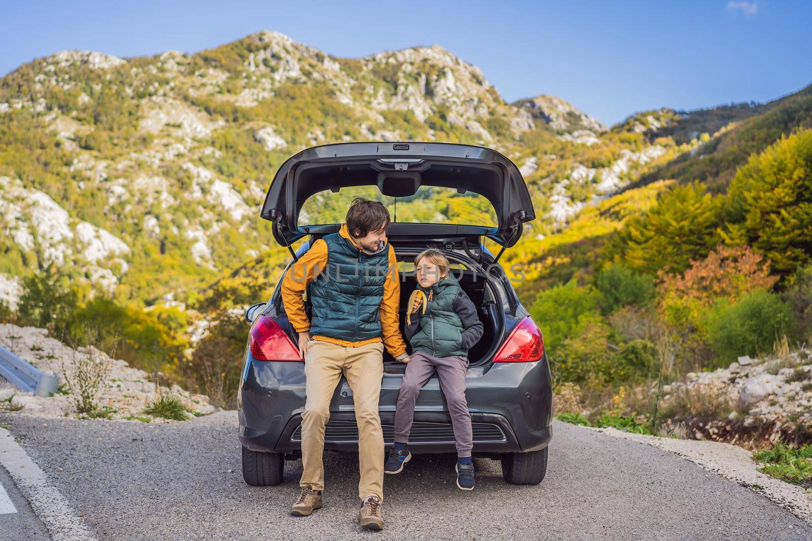 Dad and son are resting on the side of the road on a road trip. Road trip with children concept by galitskaya