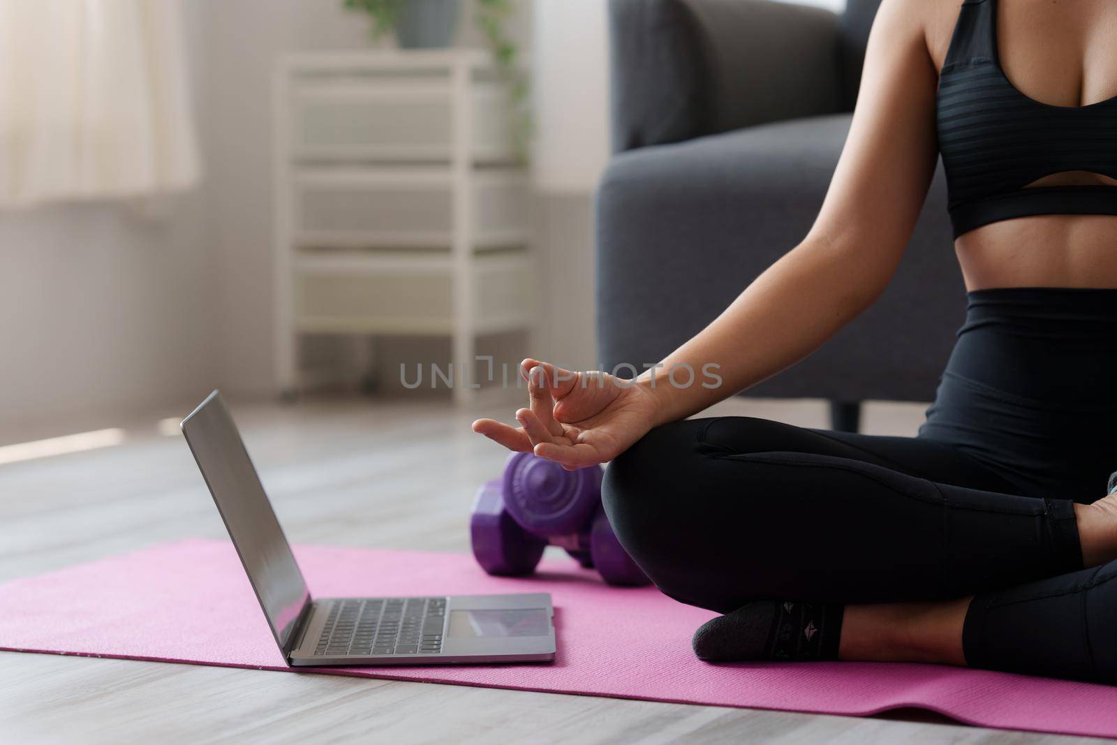 Young woman practicing yoga follow teacher in laptop online class at home. Calmness and relax concept. by itchaznong