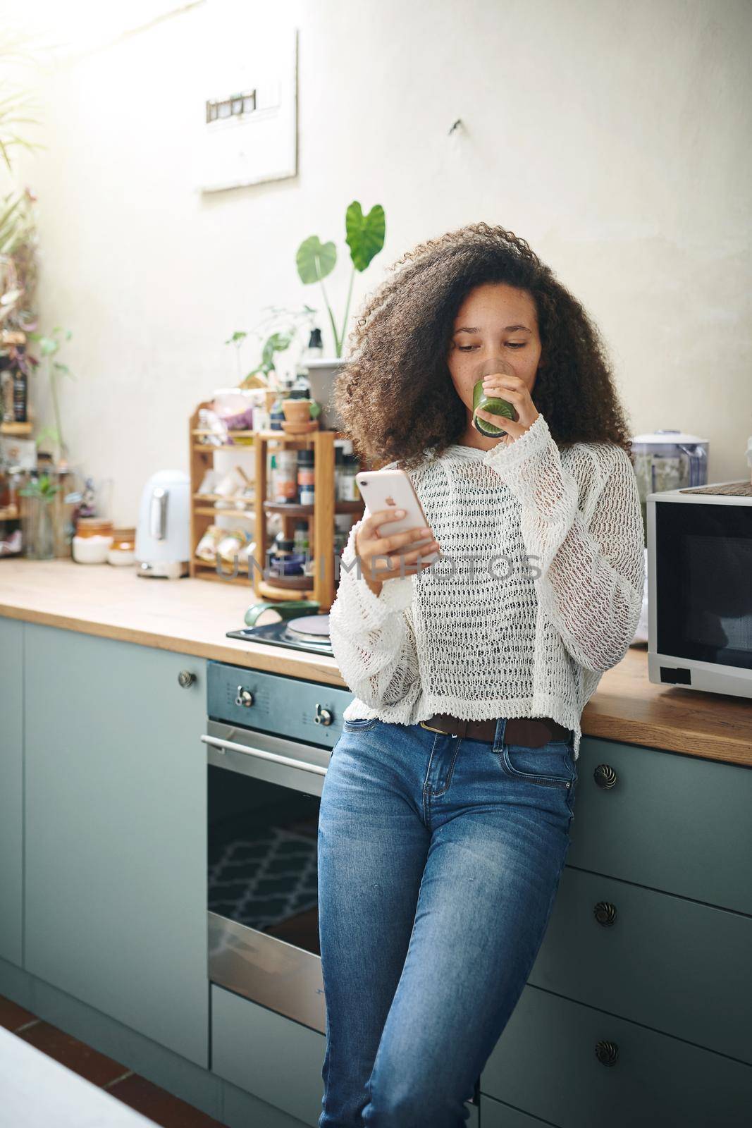 Girl browsing on social media while enjoying her green smoothie. High resolution stock photo