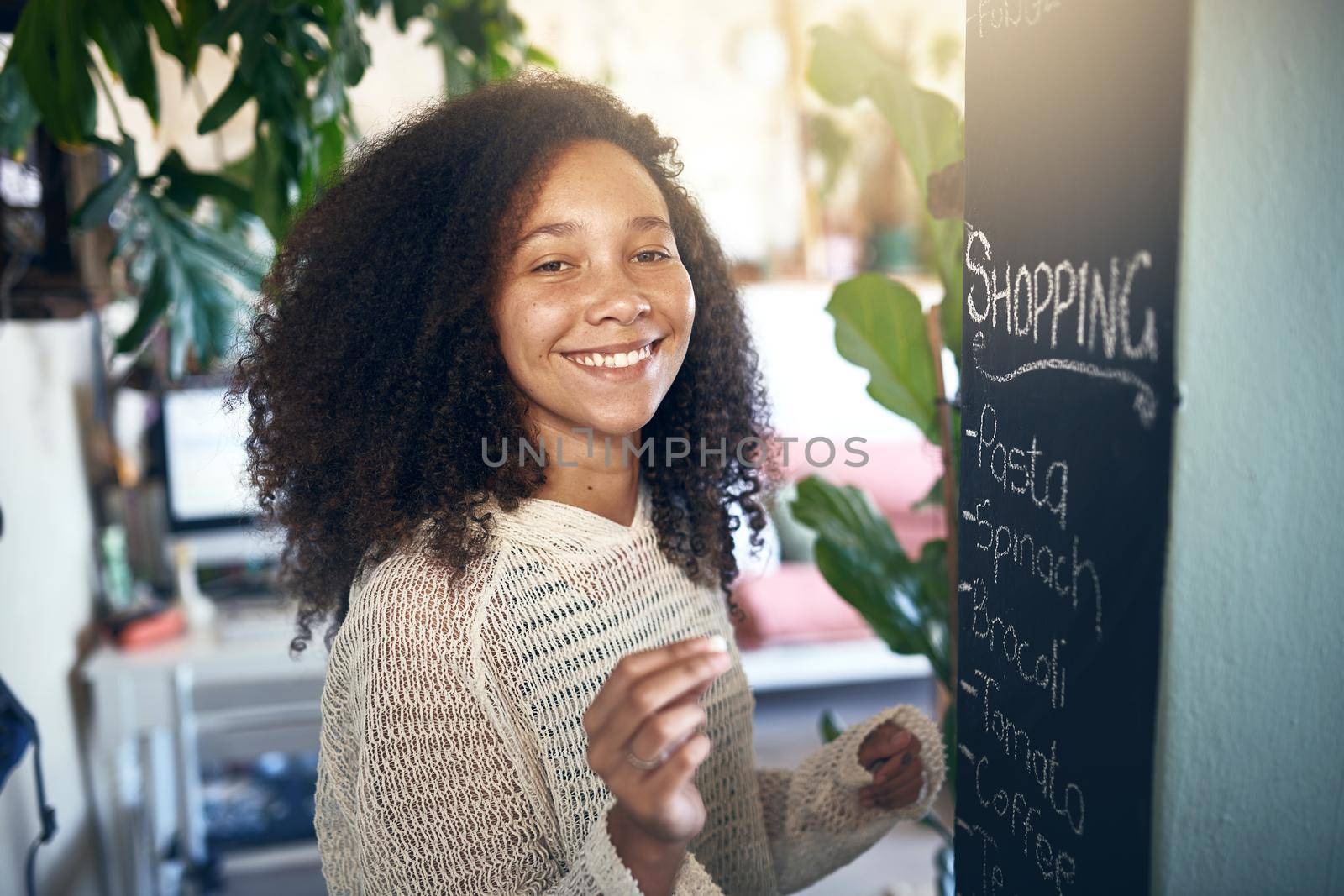 Beautiful young girl smiling at camera while making a shopping list. High quality stock photo