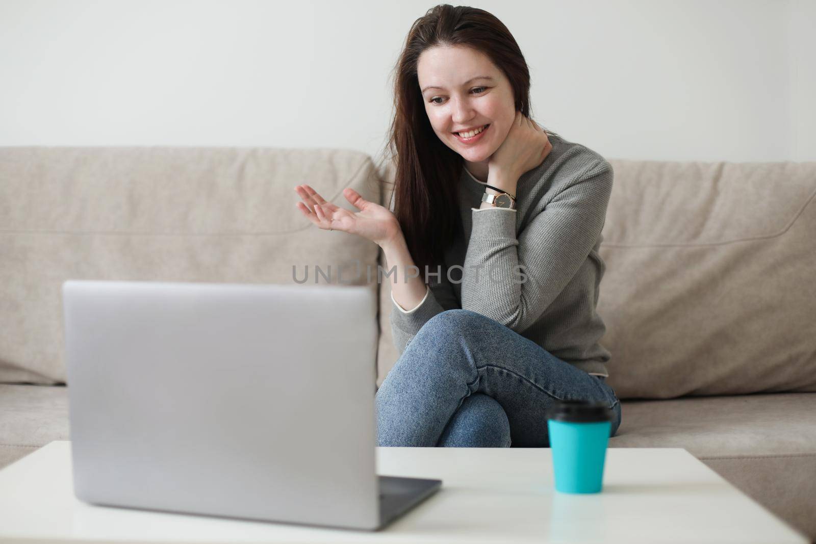 Mother and her daughter using video chat on laptop sitting on cozy sofa at home, watching video