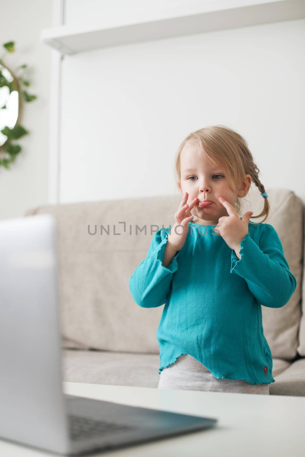 little girl uses a laptop video chat to communicate learning at home, child studying online