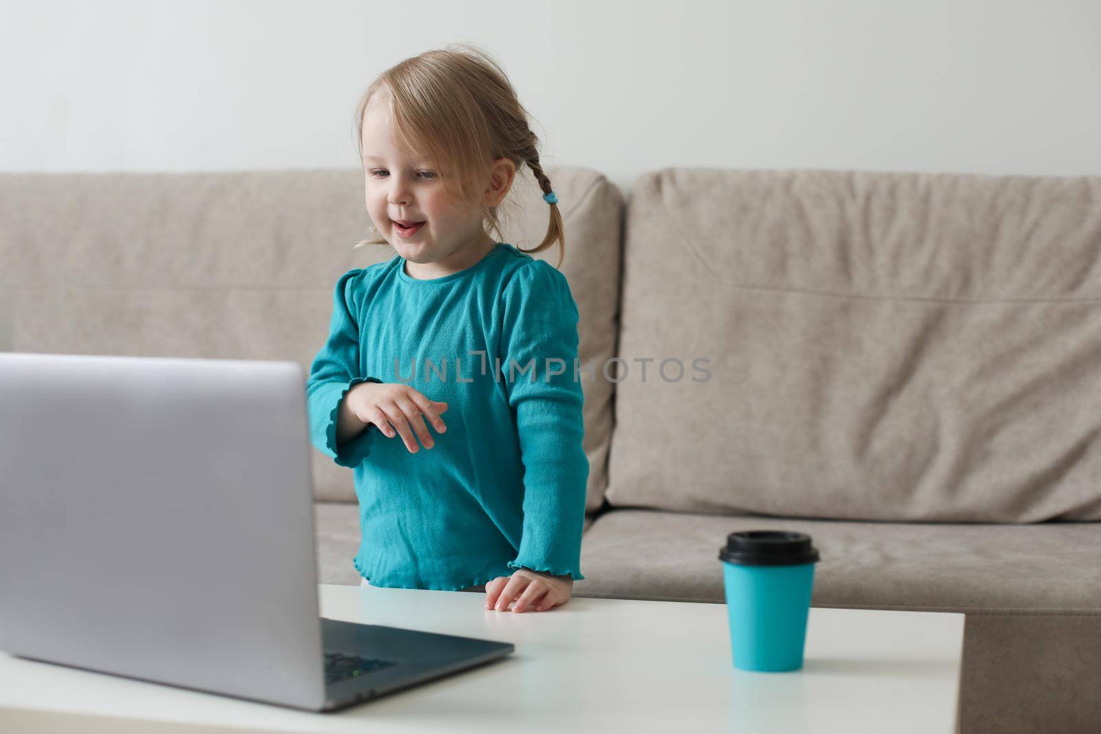 little girl uses a laptop video chat to communicate learning at home, child studying online