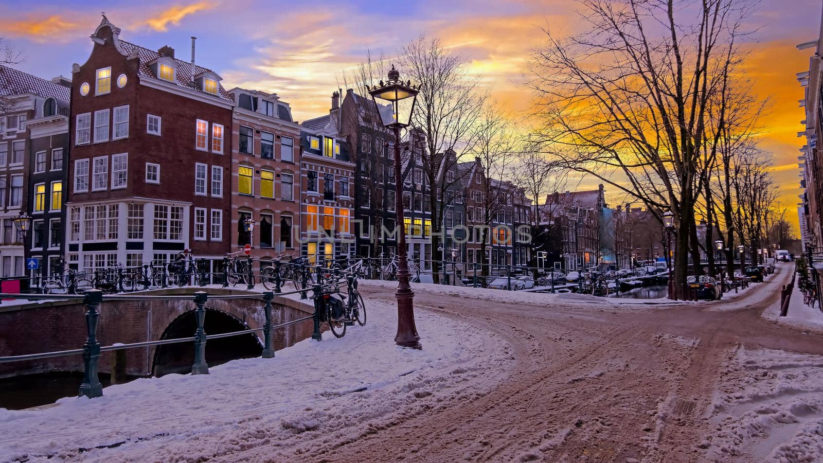 City scenic from a snowy Amsterdm in winter in the Netherlands at sunset
