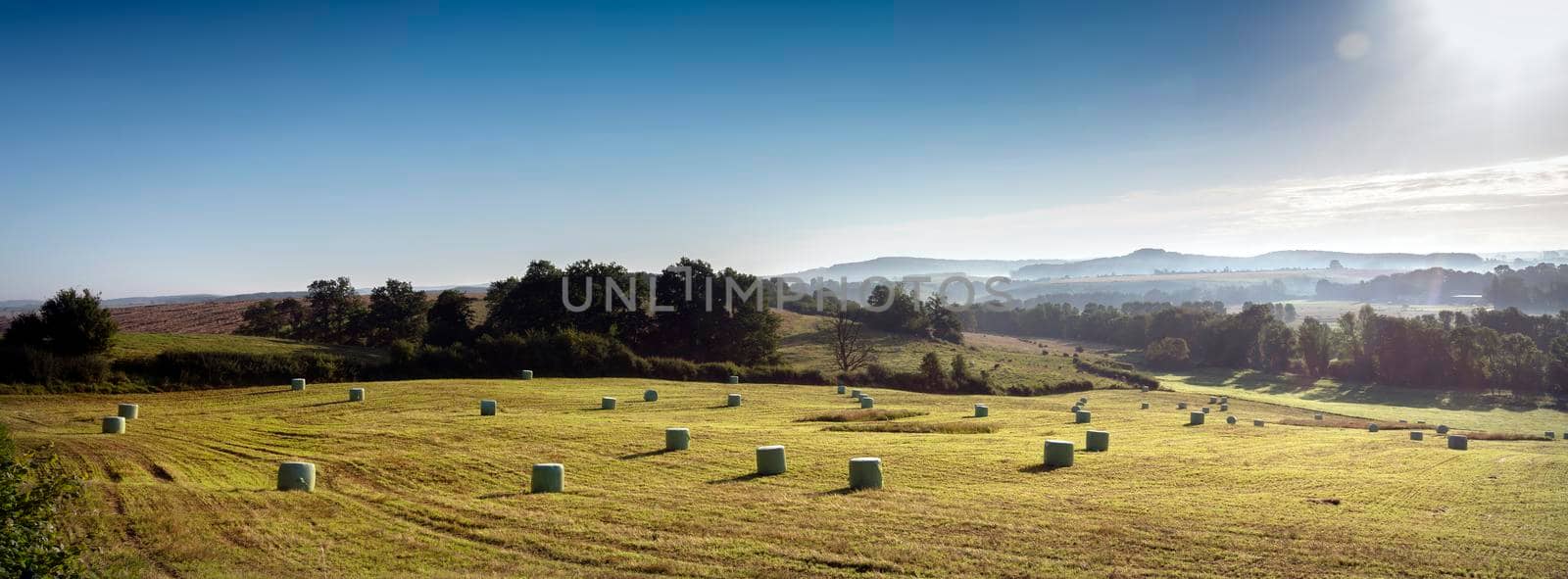 foggy early morning landscape with hay bales under blue sky in french ardennes near charleville in northern france