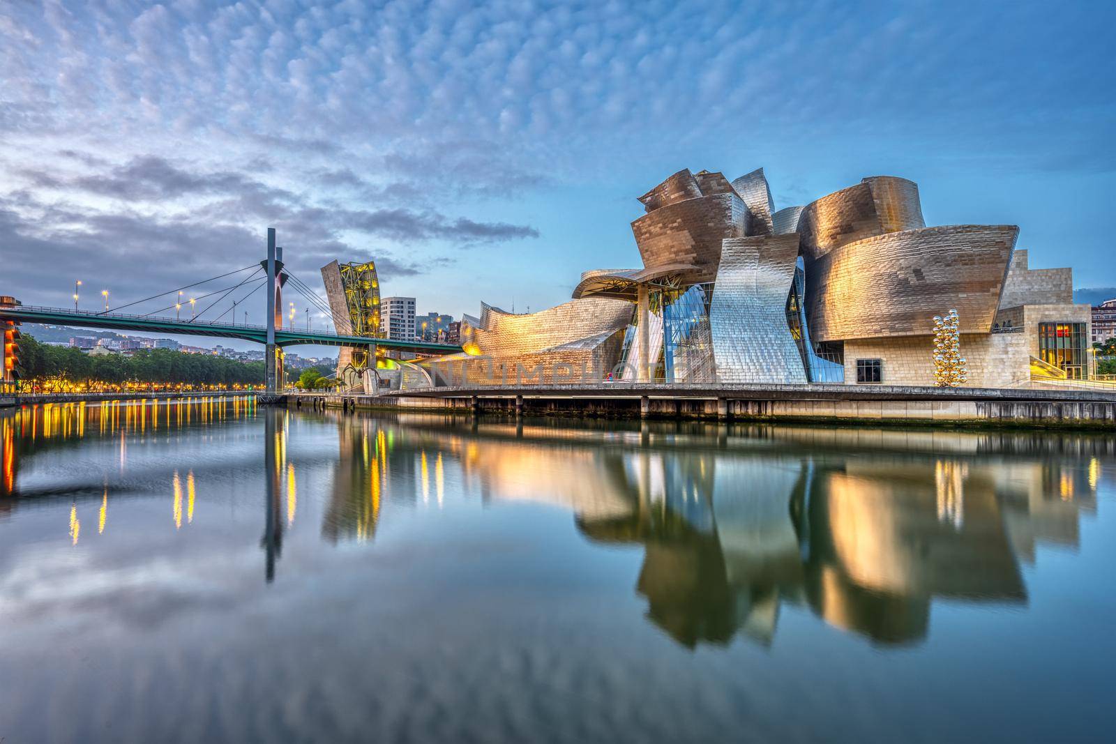BILBAO, SPAIN - July 10, 2021: The futuristic Guggenheim Museum reflected in the River Nervion before sunrise
