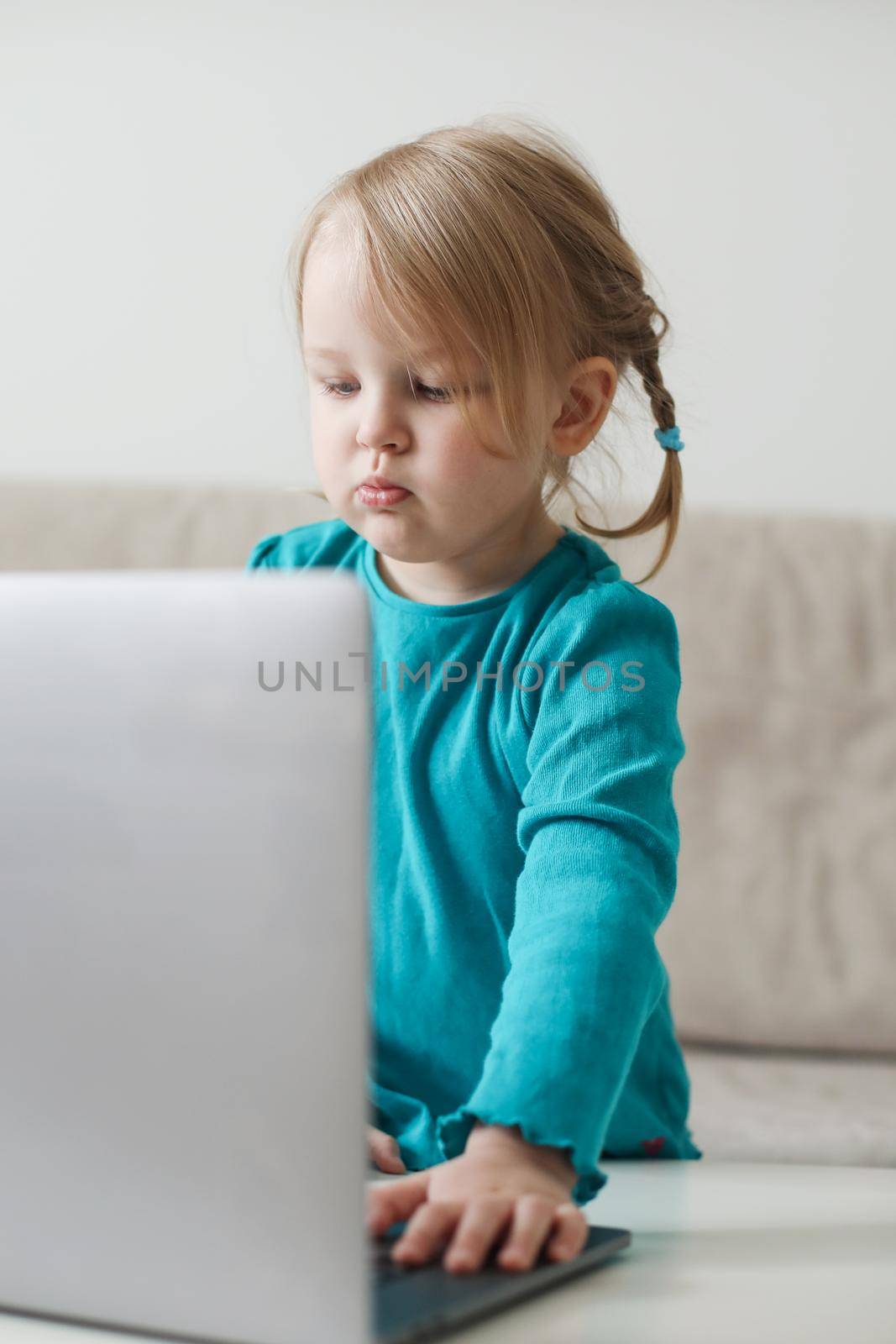 little girl uses a laptop video chat to communicate learning at home, child studying online