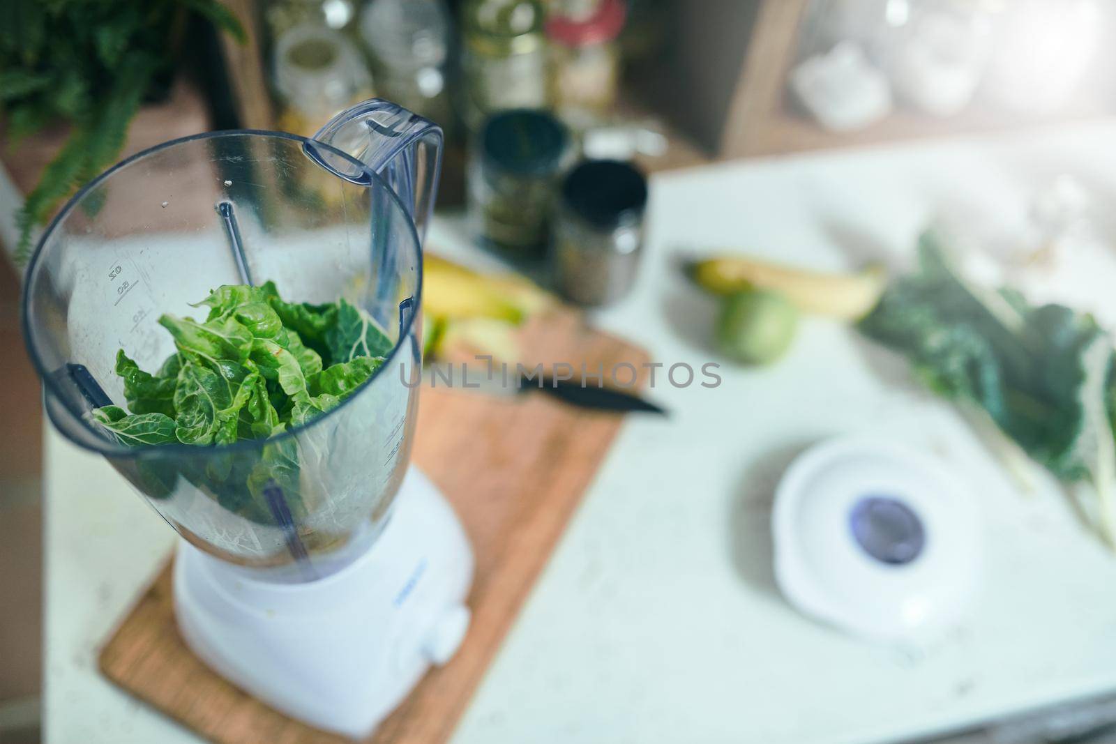 Still shot of blender with greens on wooden cutting board