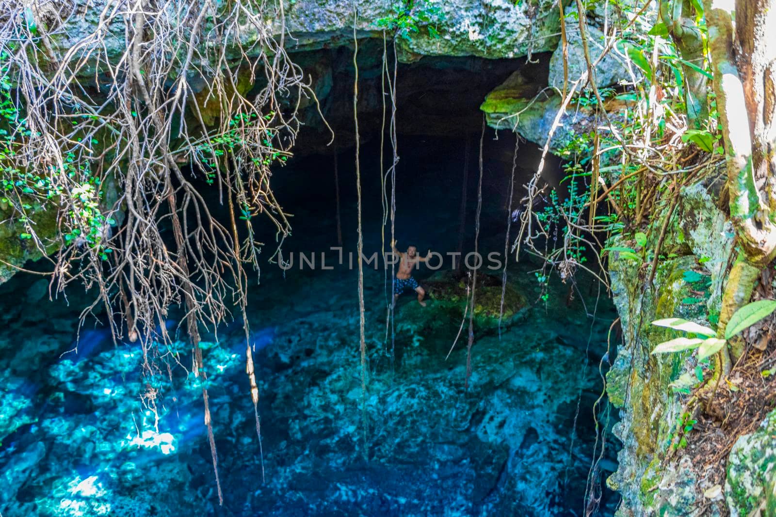 Tourist guide blue turquoise water limestone cave sinkhole cenote Mexico. by Arkadij