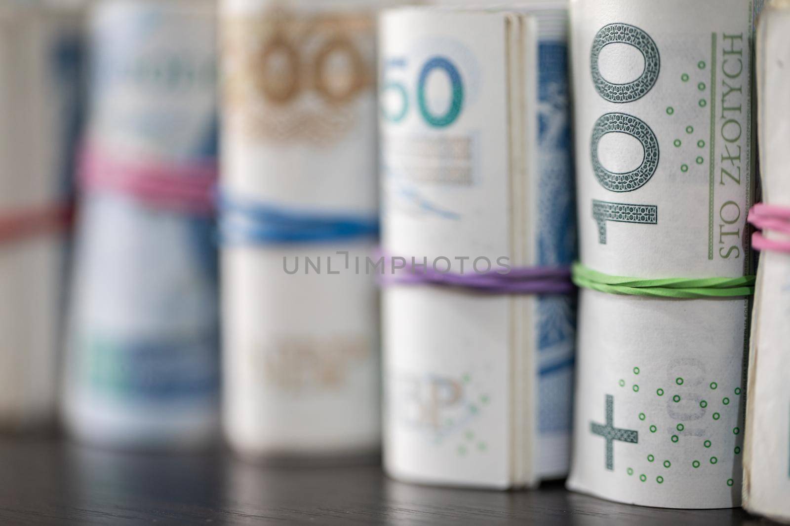 Savings rolled up and displayed on a table. Poland's national paper cash. Banknotes rolled up and tied together with a rubber band.