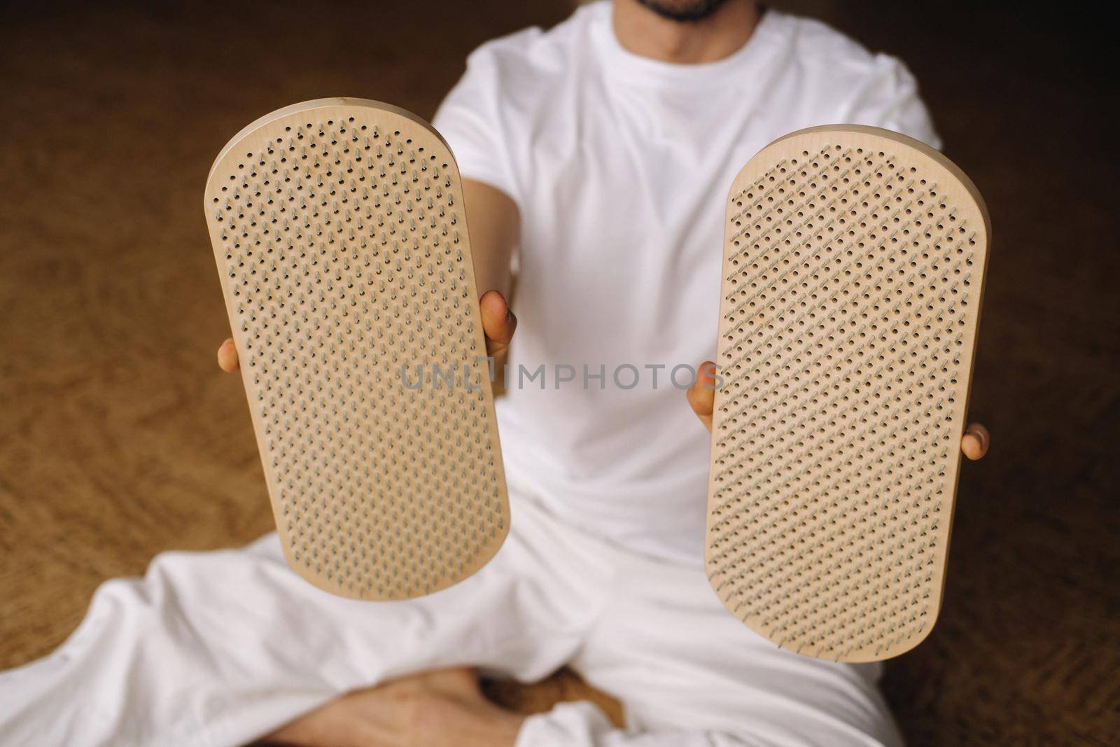 A man holds in his hands boards with nails for yoga classes by Lobachad