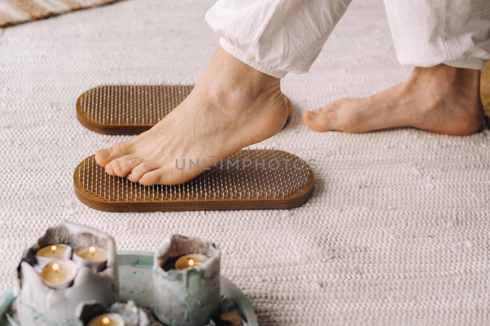 The man's feet are next to boards with nails. Yoga classes.