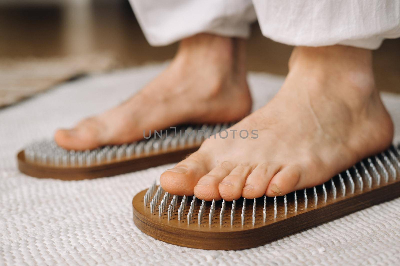 The man's feet are next to boards with nails. Yoga classes by Lobachad