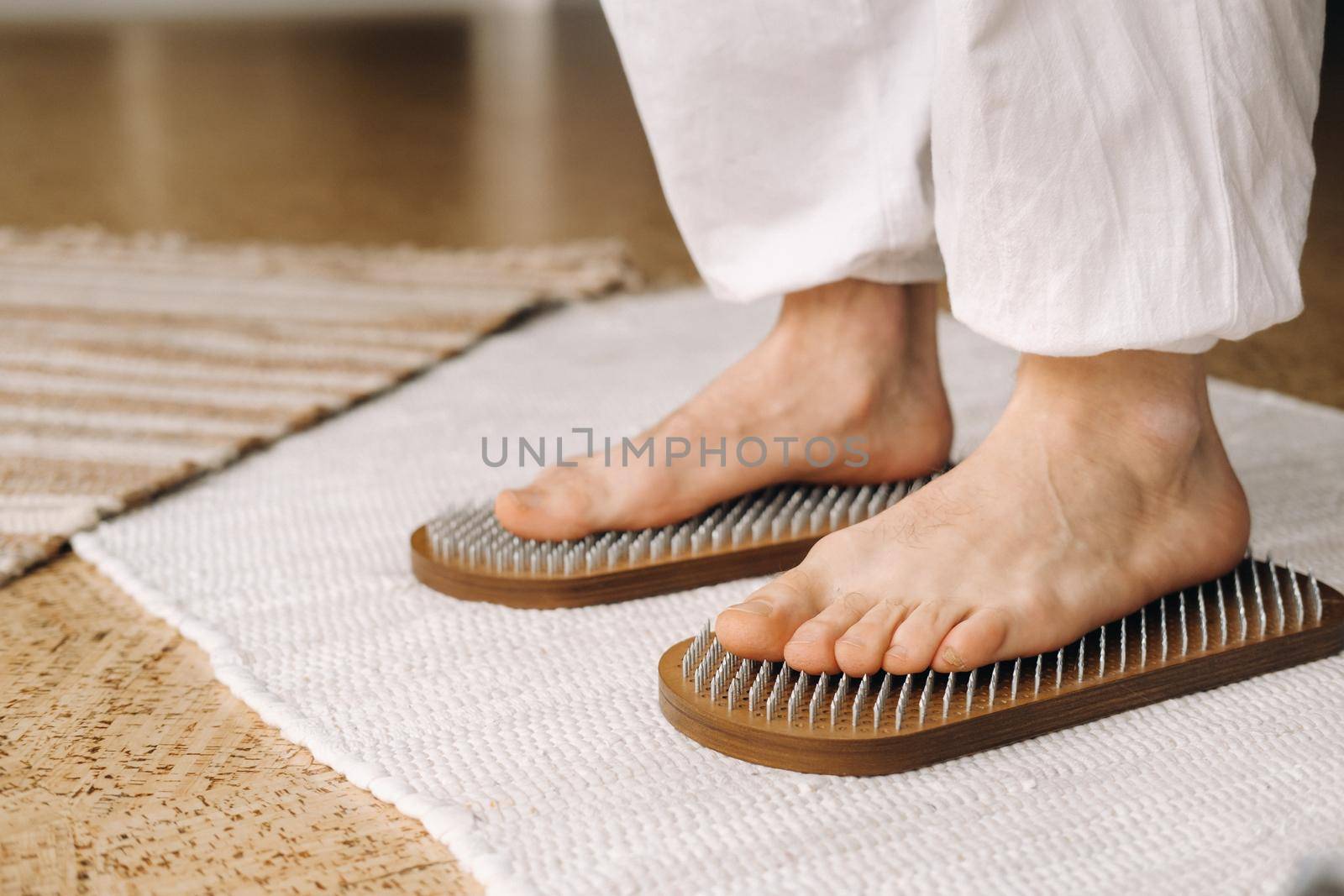 The man's feet are next to boards with nails. Yoga classes.