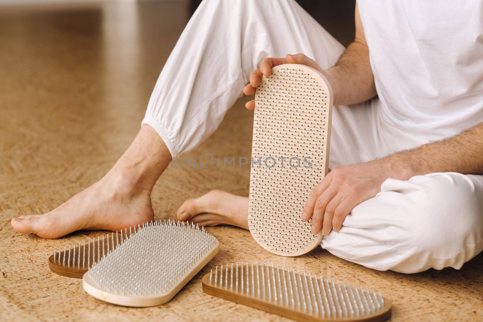 A man holds in his hands boards with nails for yoga classes by Lobachad