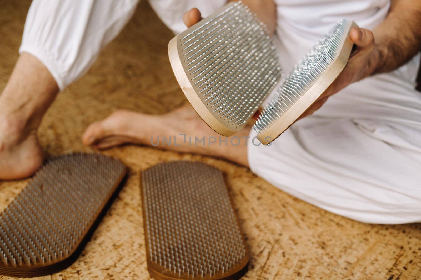 A man holds in his hands boards with nails for yoga classes by Lobachad