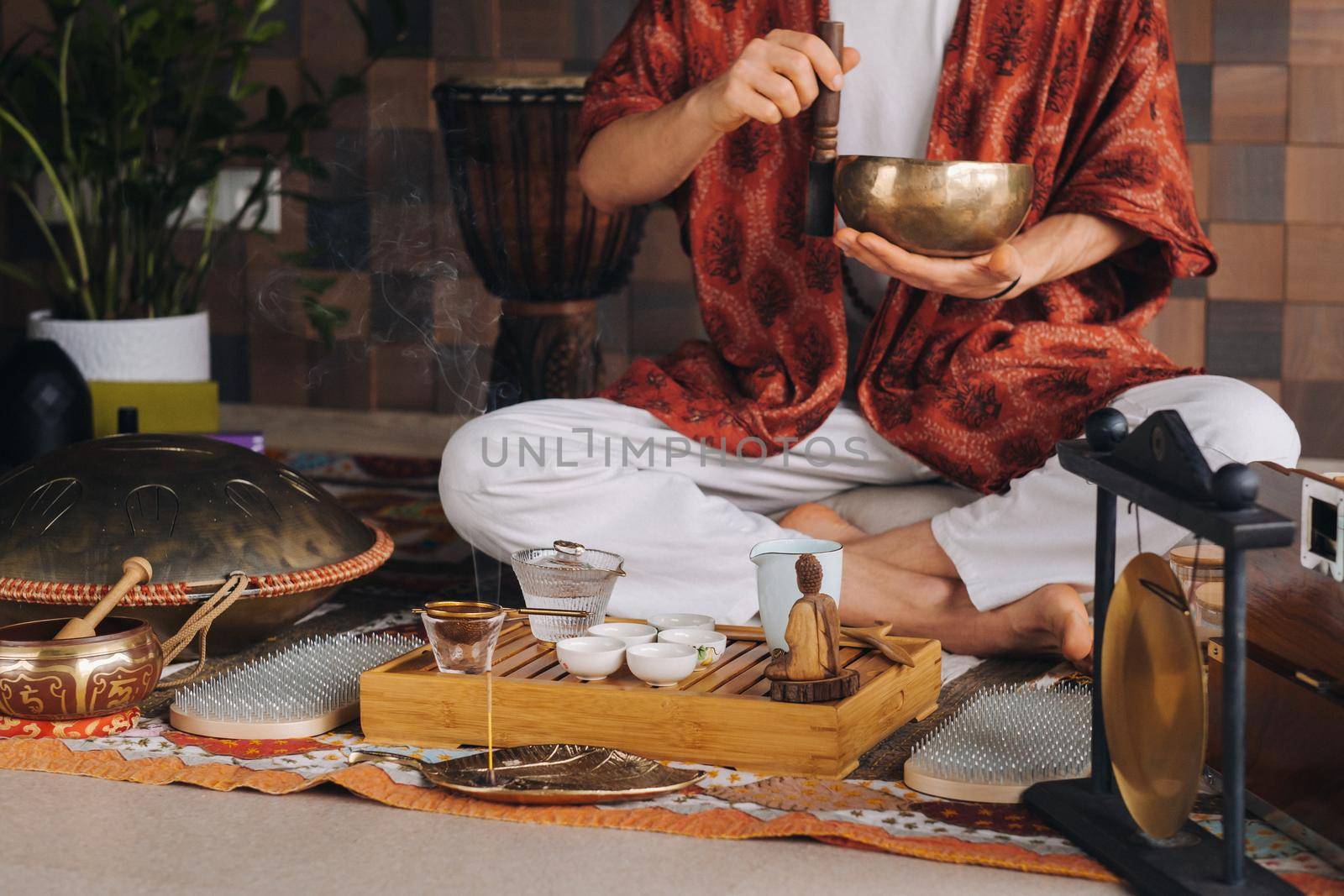 Tibetan singing bowl in the hands of a man during a tea ceremony by Lobachad
