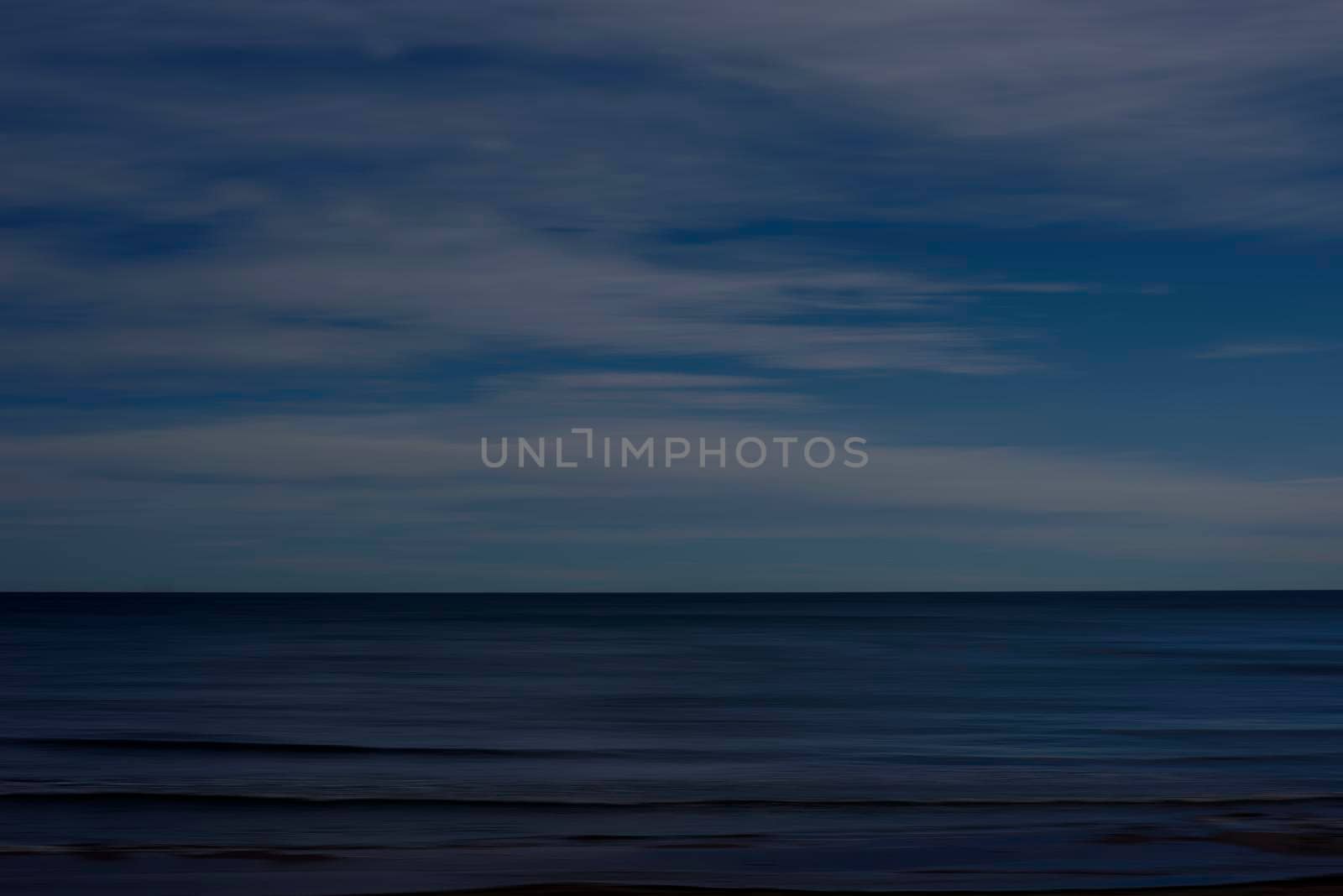 Background of a beach and sky with clouds. Mystic movement, fleeing clouds, dark, moving water