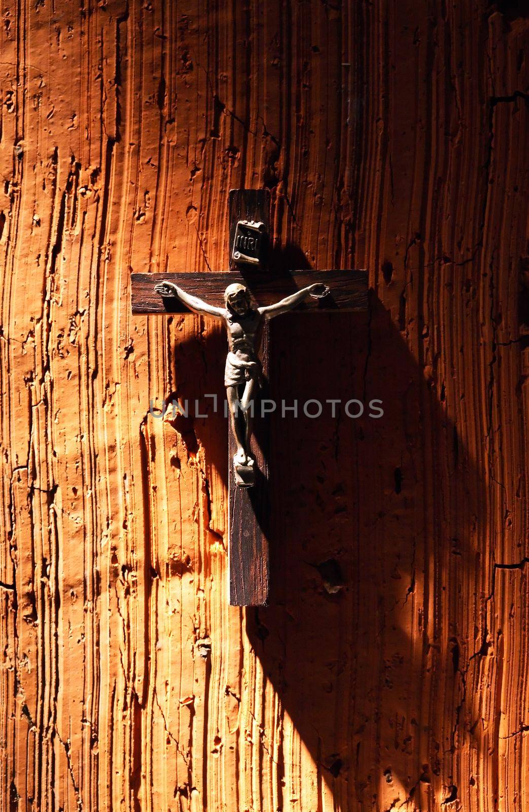 Religion symbol. Small crucifixion on brick wall under beam of light