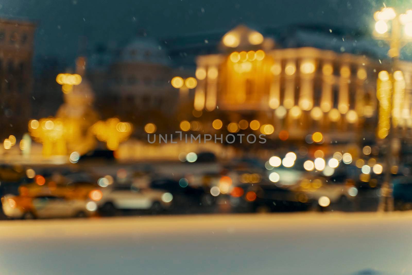 Winter blurred background with falling snow on the background of a city street. The concept of the first snow or snowfall in winter.