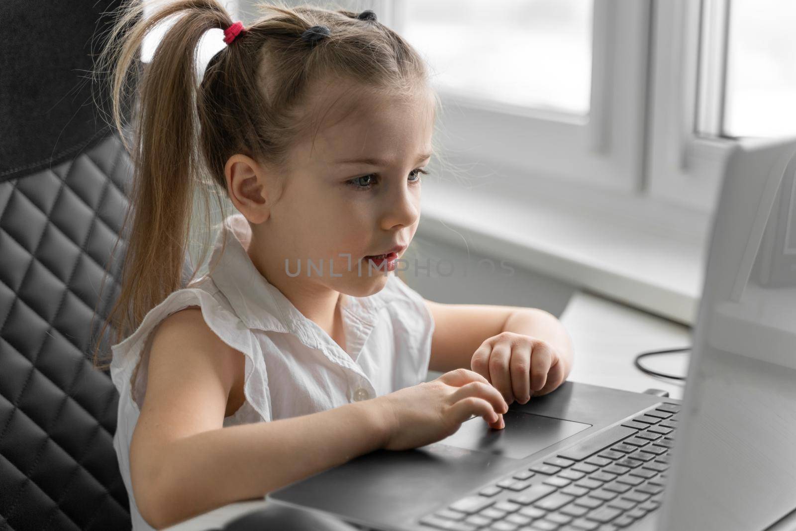 cute little caucasian girl studying online at home