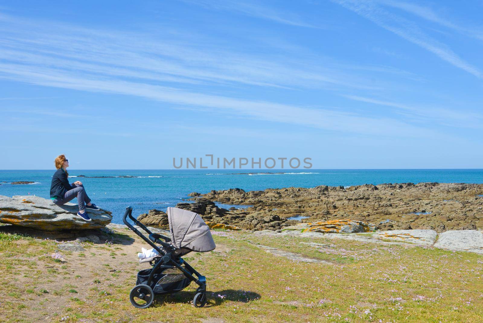 Mother strolling with a baby looks at the Atlantic Ocean