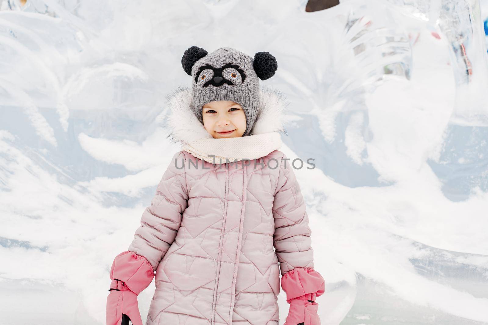 little girl in a knitted hat and scarf and ice sculptures