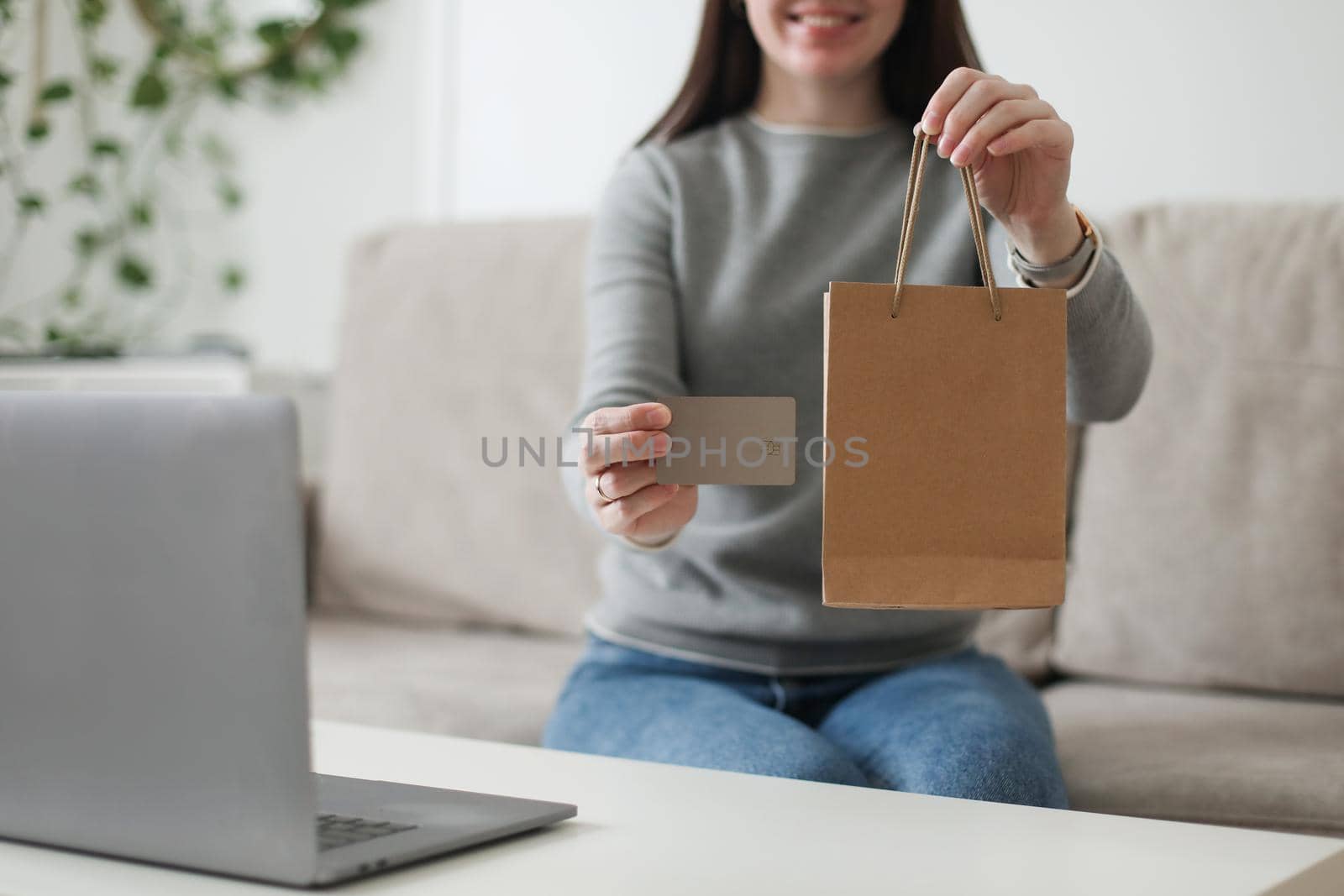 Young woman holding credit card and using laptop at home. Paying online, home shopping, internet banking, electronic store concept.