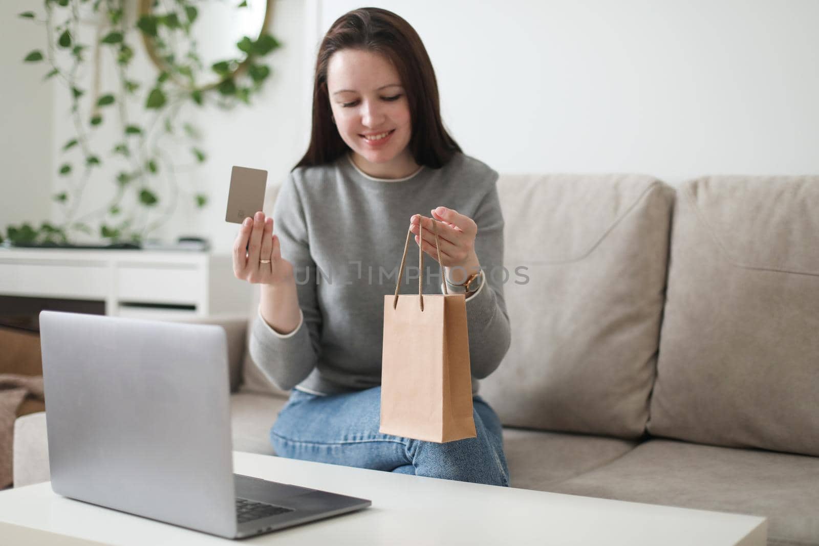 Young woman holding credit card and using laptop at home. Paying online, home shopping, internet banking, electronic store concept.