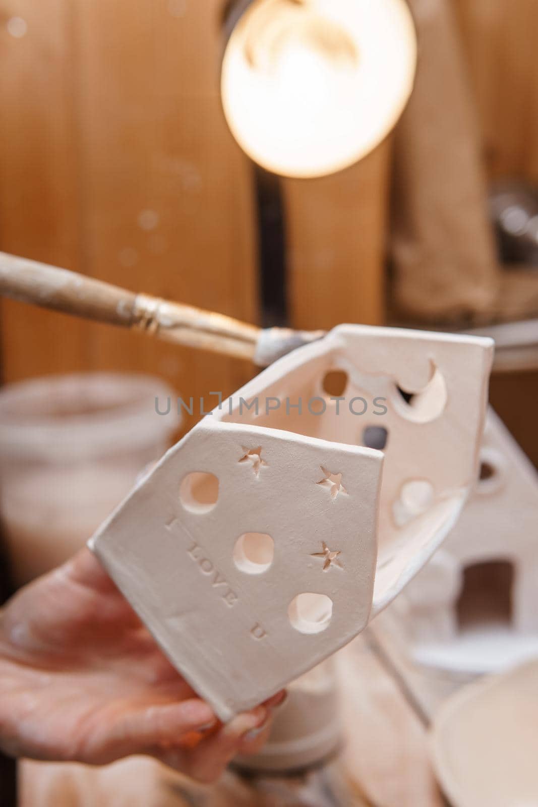 A master ceramist holds a clay product in his hands. Making a ceramic candle holder from clay. The process of coating the candlestick with glaze. Close-up.