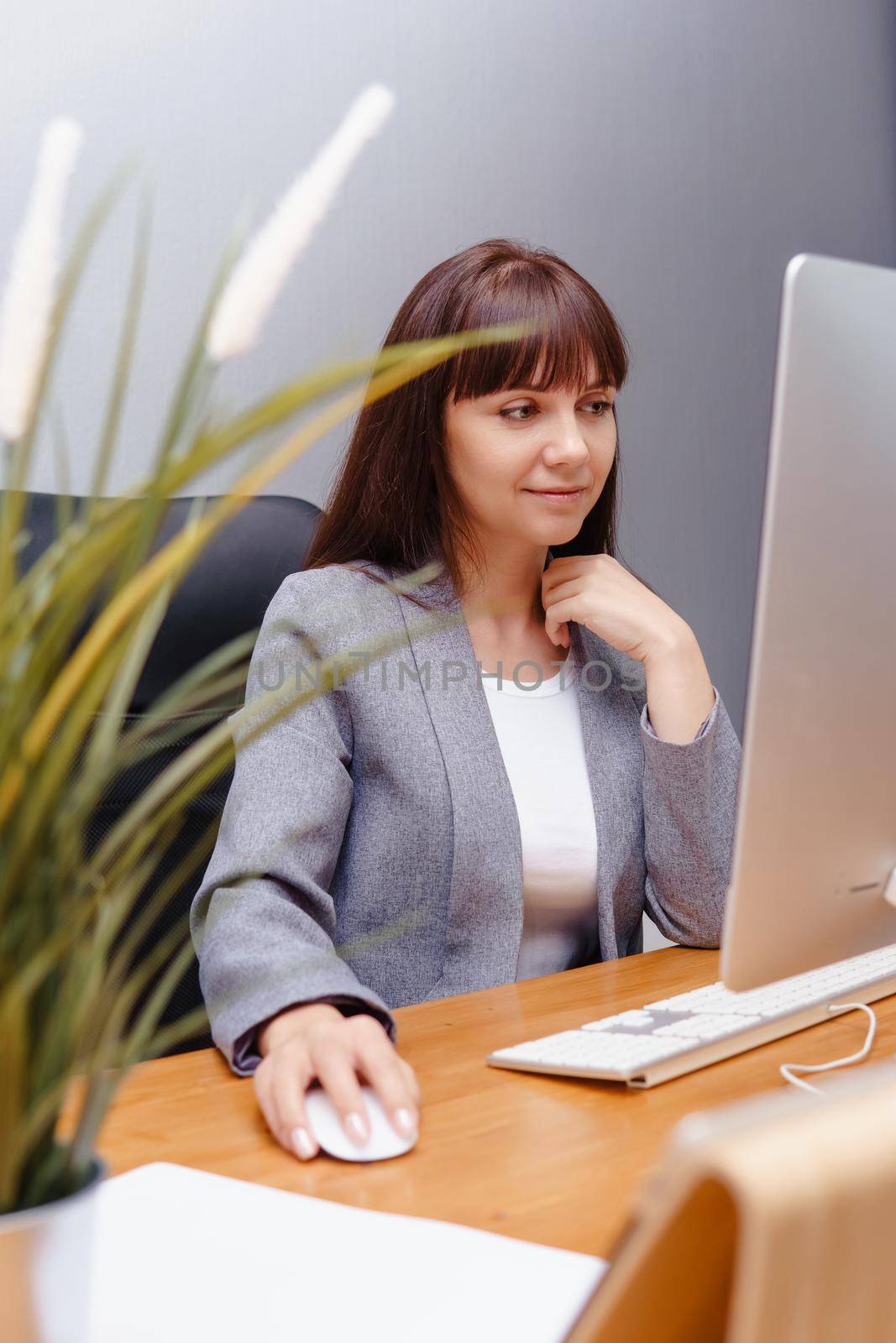 A brunette woman at a computer in the workplace. Business concept.