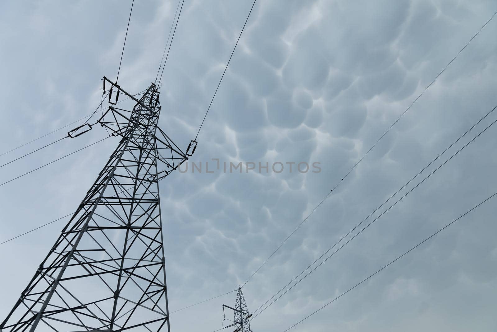 Steel pole built on a truss base to transmit high voltage against a background of storm clouds. Electricity.