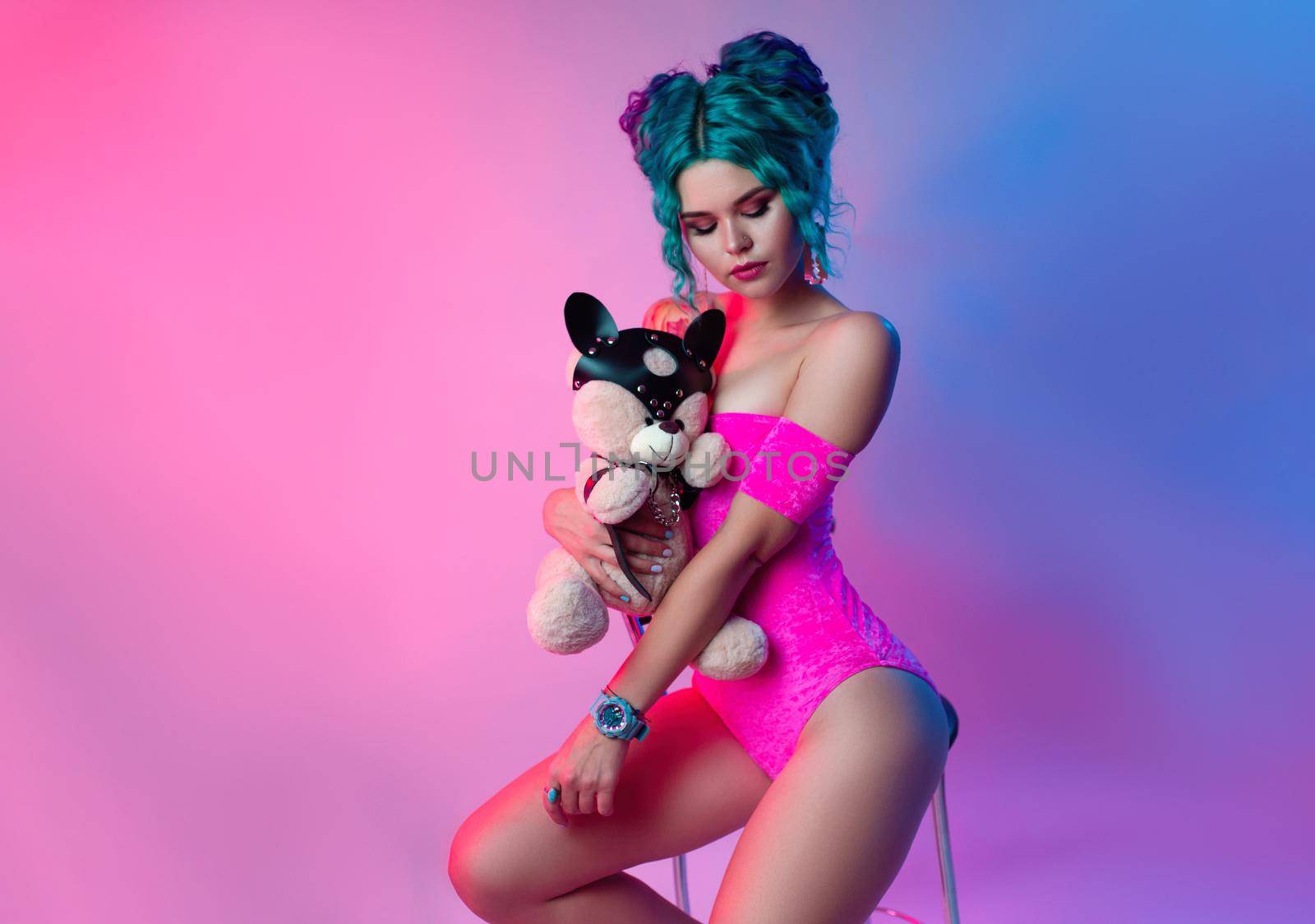 the woman with blue hair and a pink bodysuit is sitting on a bar stool