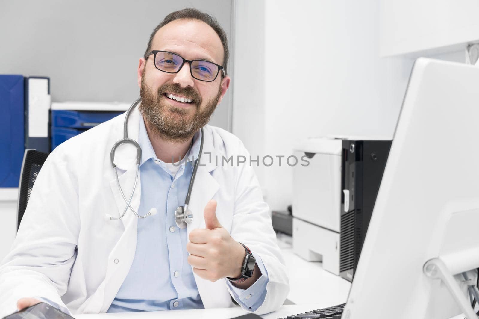 Friendly male doctor smiling and giving thumb up sign by HERRAEZ