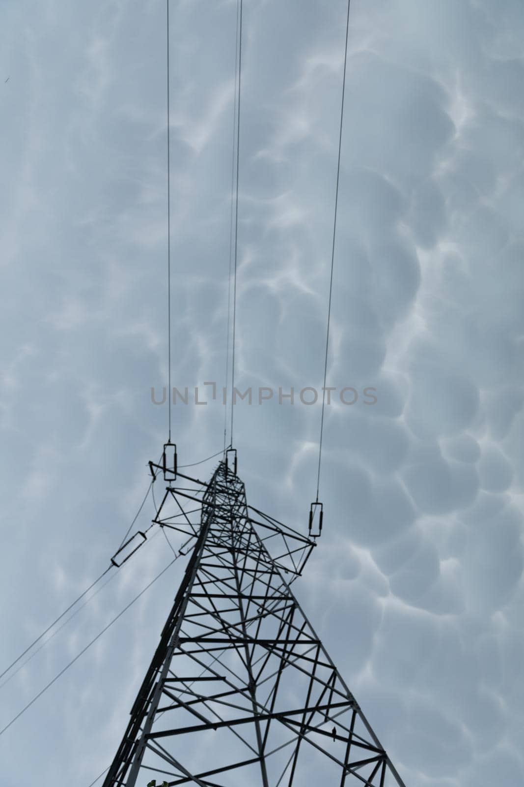 High voltage power line against a backdrop of billowing storm clouds. The forces of nature and modern electricity.