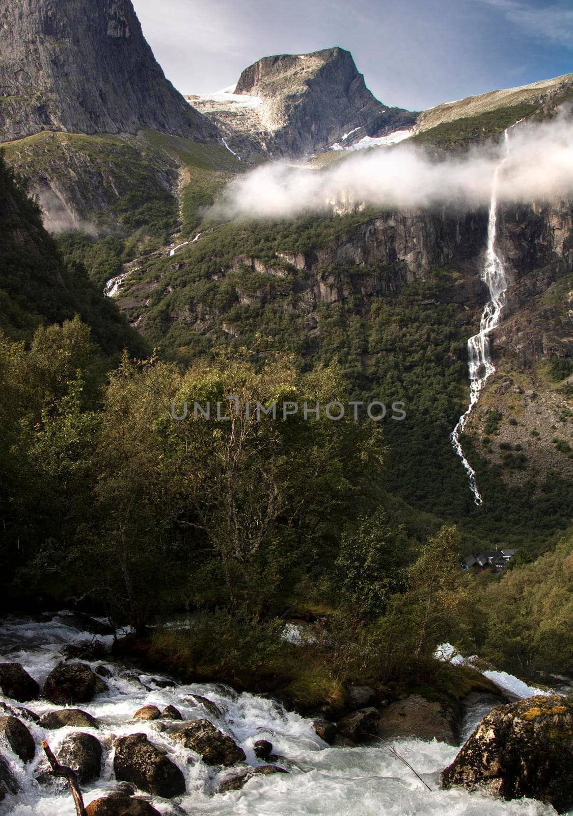 Landscape showing some peaks and a thin waterfall under a special lonely cloud in Norway