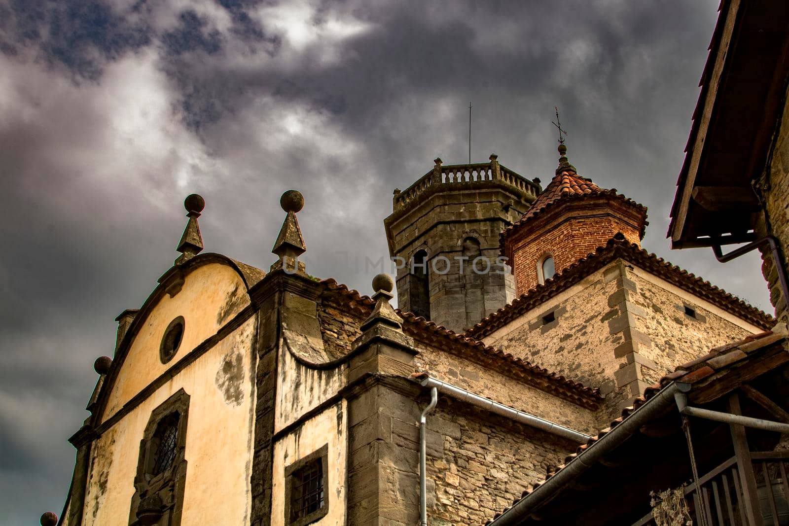 Church facade and towers in a Catalan town called Rupit under a cloudy sky