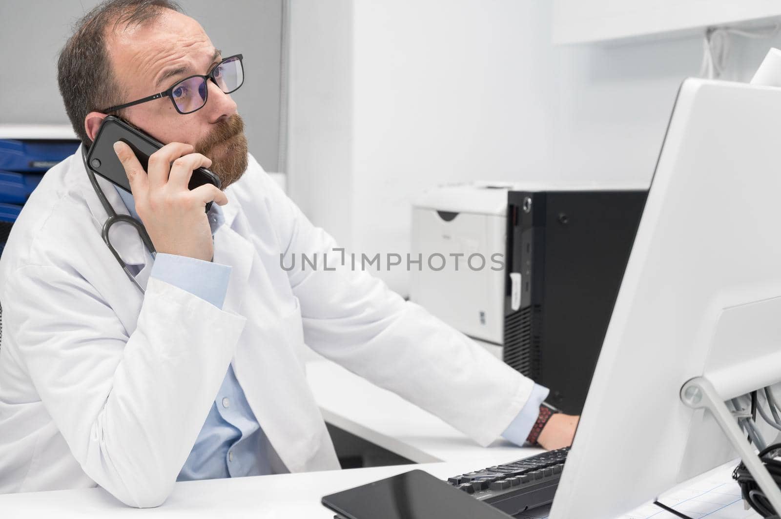 Doctor in office talking on phone by HERRAEZ