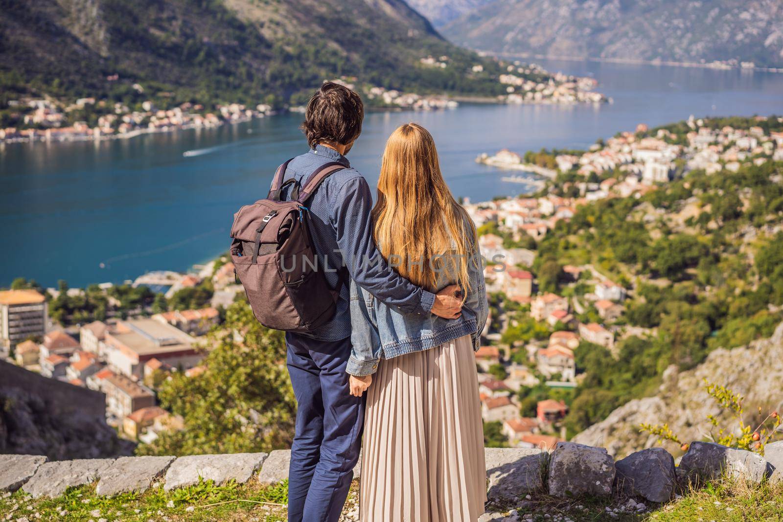 Couple woman and man tourists enjoys the view of Kotor. Montenegro. Bay of Kotor, Gulf of Kotor, Boka Kotorska and walled old city. Travel to Montenegro concept. Fortifications of Kotor is on UNESCO World Heritage List since 1979 by galitskaya