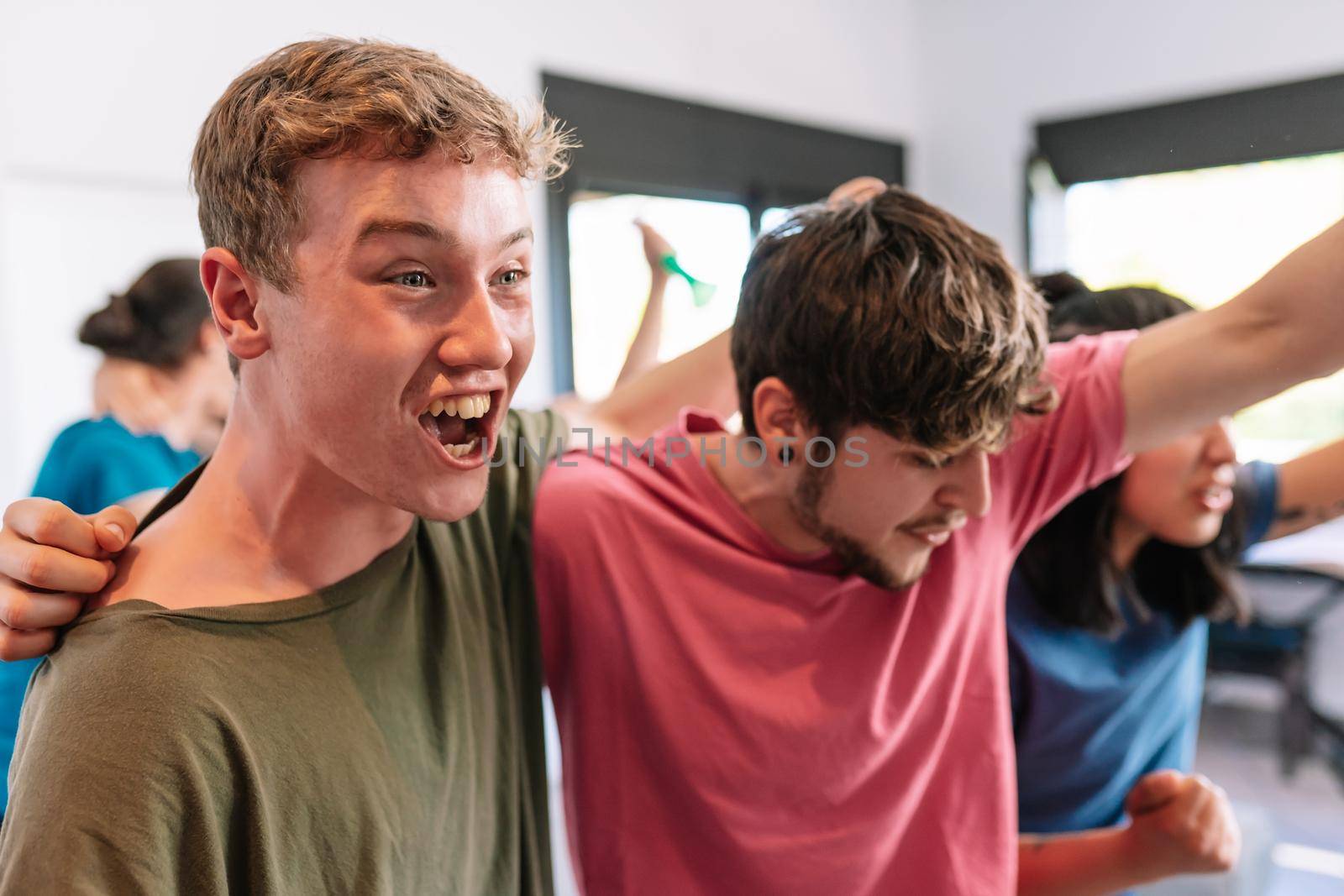 friends screaming with joy watching e-sports on TV after their team's victory. group of young people partying at home. by CatPhotography