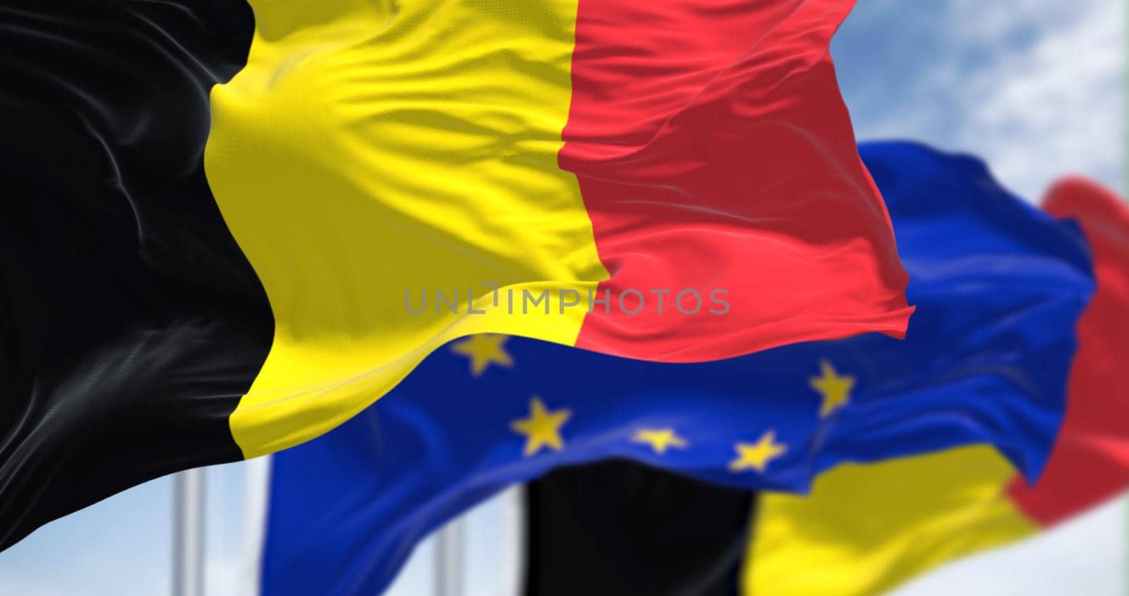 Detail of the national flag of Belgium waving in the wind with blurred european union flag in the background on a clear day. Democracy and politics. European country. Selective focus.