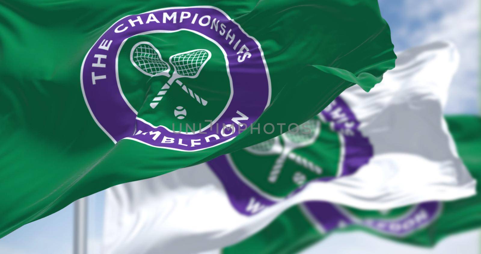 London, UK, April 2022: three flags with the The Championships Wimbledon logo waving in the wind. Wimbledon Championships is a major tennis tournament scheduled in late June each year