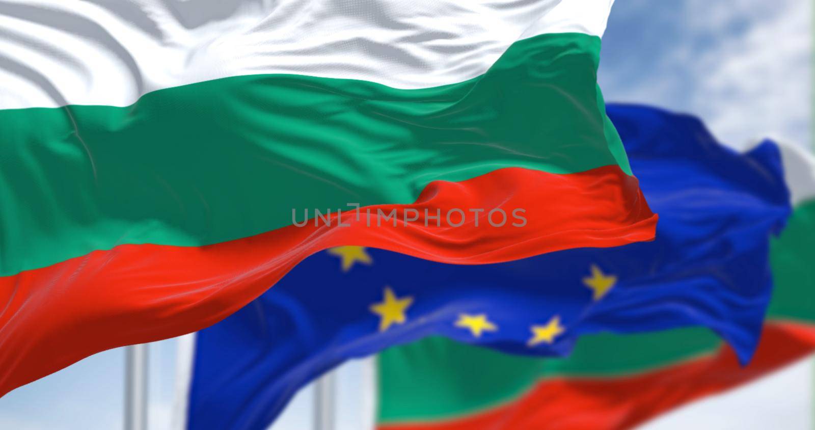 Detail of the national flag of Bulgaria waving in the wind with blurred european union flag in the background on a clear day. Democracy and politics. European country. Selective focus.