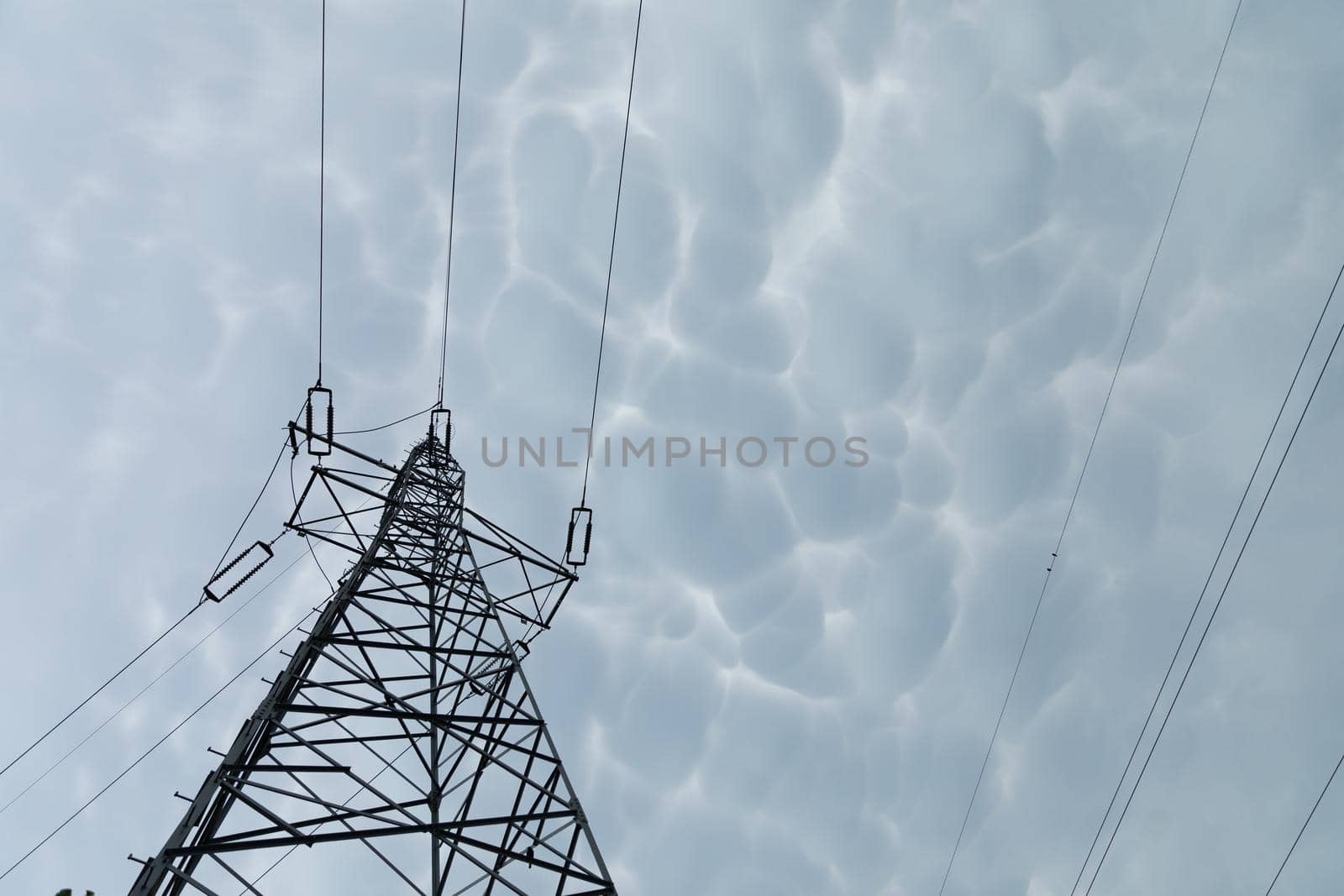 High voltage power line against a backdrop of billowing storm clouds. The forces of nature and modern electricity.