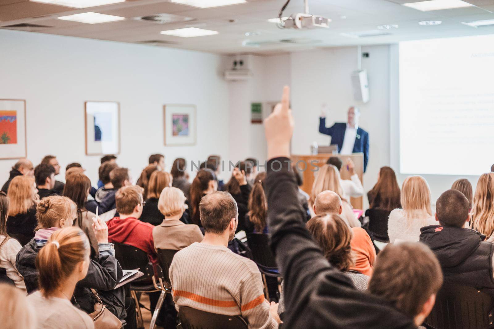 I have a question. Group of people sitting at the chairs in conference hall, raising their hands. Workshop at university. Business and Entrepreneurship event.