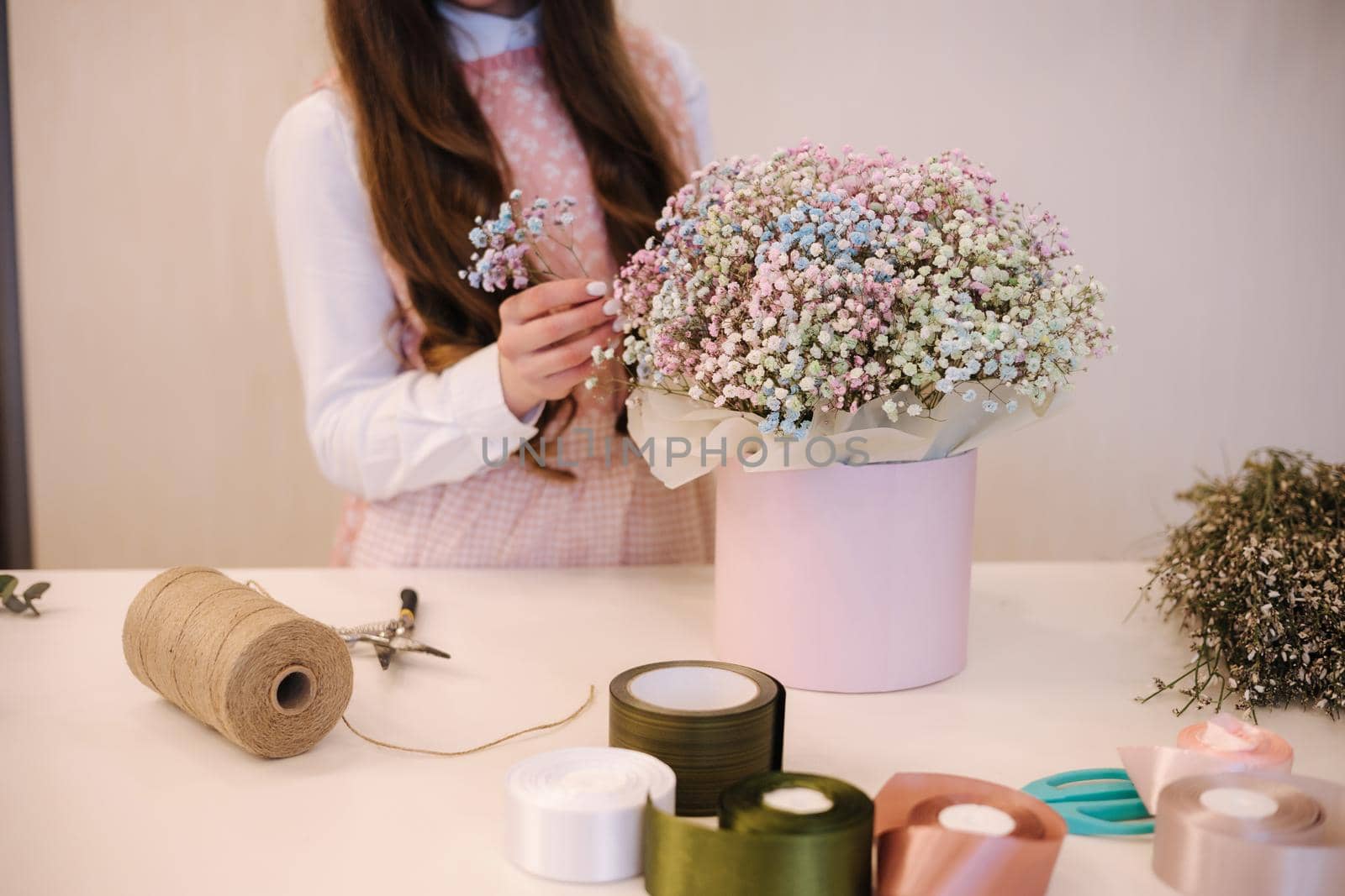 Woman make spring bouquet. Female florist wrapping beautiful bouquet of spring flowers in pack paper on the table. Beautiful flower composition