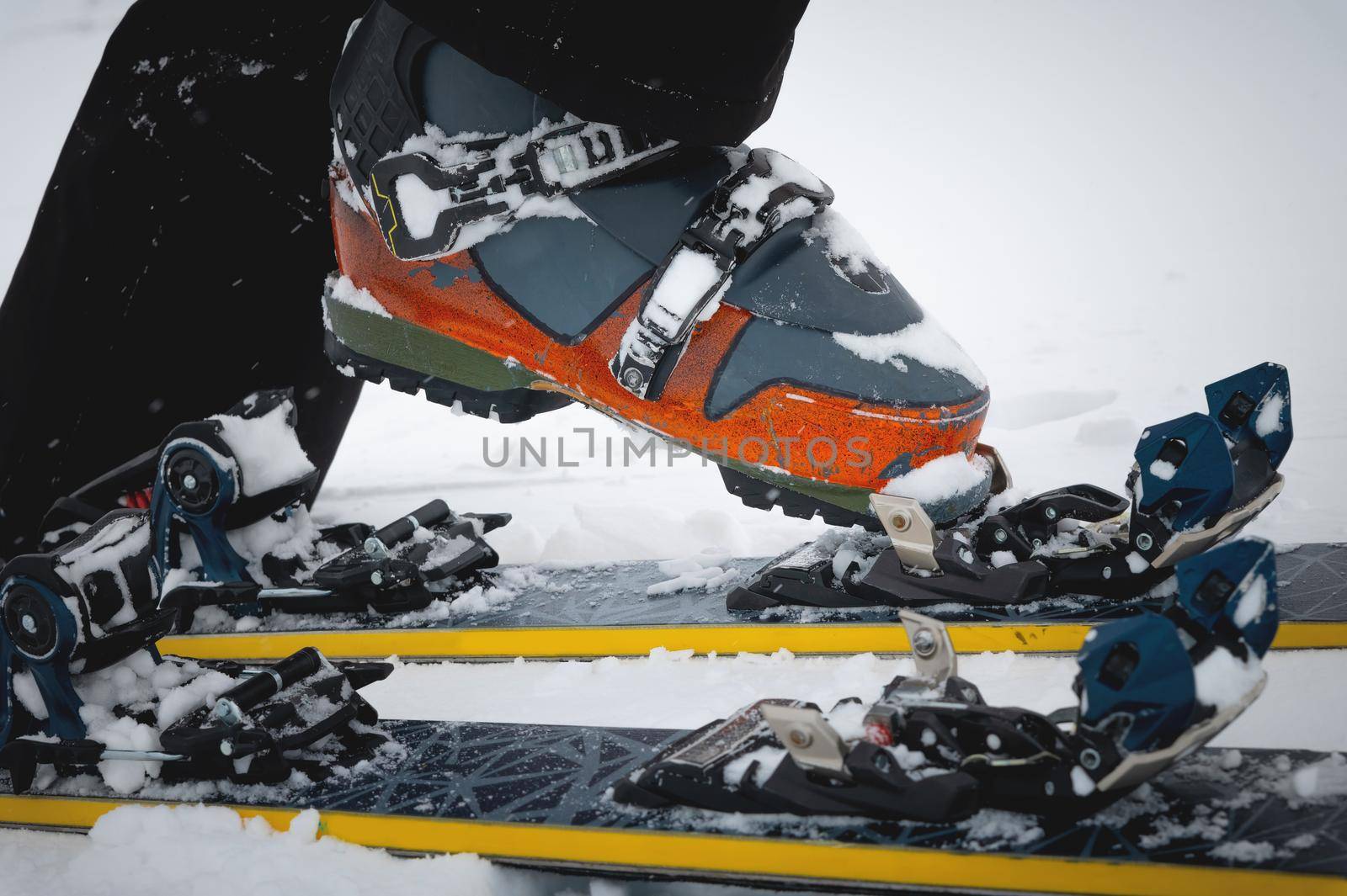 Close-up of freeride ski boots on snow. Skitour concept. Used worn boots on a male skier against the background of a glacier in cloudy weather in the mountains.